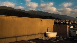 A rooftop with a large bathtub, a concrete wall, and a view of a town and mountains in the background. - Dali Wenyue Hotel (Erhai Ecological Corridor Branch) (Dali City)