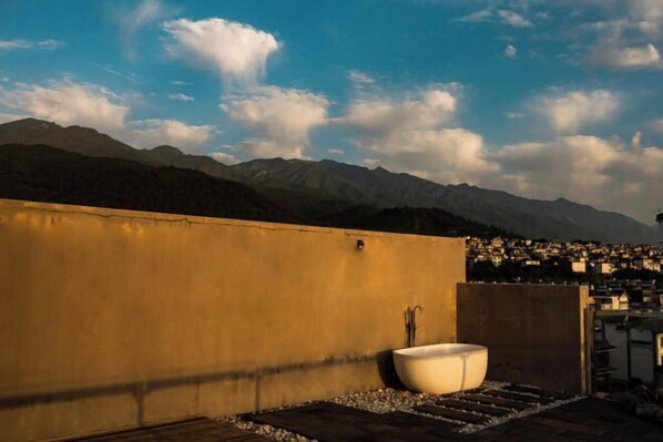 A rooftop with a large bathtub, a concrete wall, and a view of a town and mountains in the background. - Dali Wenyue Hotel (Erhai Ecological Corridor Branch) (Dali City)