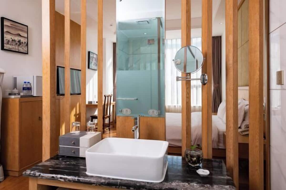A modern bathroom with a rectangular sink, a glass shower enclosure, and a wooden partition.