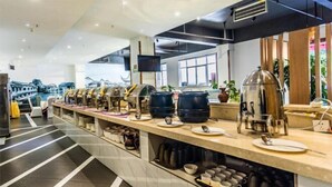 A modern breakfast bar with a variety of coffee and tea options, a flat-screen TV, and a view of a traditional building through the windows. - Dali Wenyue Hotel (Erhai Ecological Corridor Branch) (Dali City)