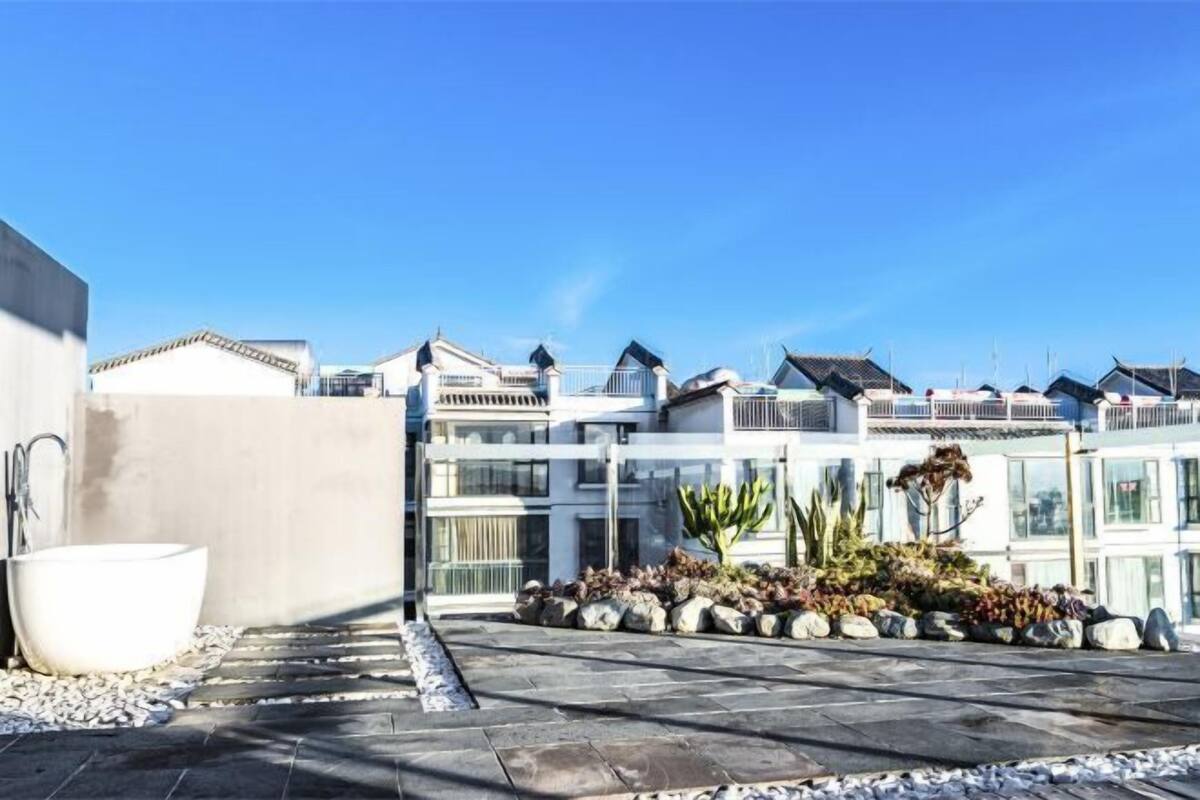 A modern building with a rooftop garden, a large white bathtub, and a clear blue sky.
