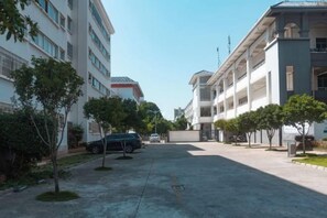 Una calle residencial con edificios de varios pisos, automóviles estacionados y árboles.