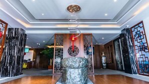 A lobby with a central stone sculpture, wooden paneling, and a ceiling with recessed lighting. - Dali Wenyue Hotel (Erhai Ecological Corridor Branch) (Dali City)