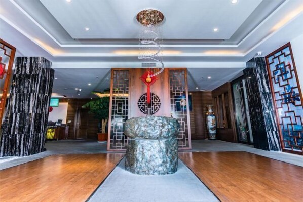 A lobby with a central stone sculpture, wooden paneling, and a ceiling with recessed lighting. - Dali Wenyue Hotel (Erhai Ecological Corridor Branch) (Dali City)