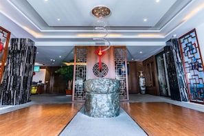 A lobby with a reception desk, a decorative stone centerpiece, and traditional Chinese architectural elements. - Dali Wenyue Hotel (Erhai Ecological Corridor Branch) (Dali City)