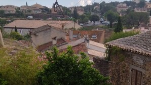 A red umbrella, a stone wall, and a view of houses and greenery. - Charmant Appartement de Village (Roquebrune-sur-Argens)