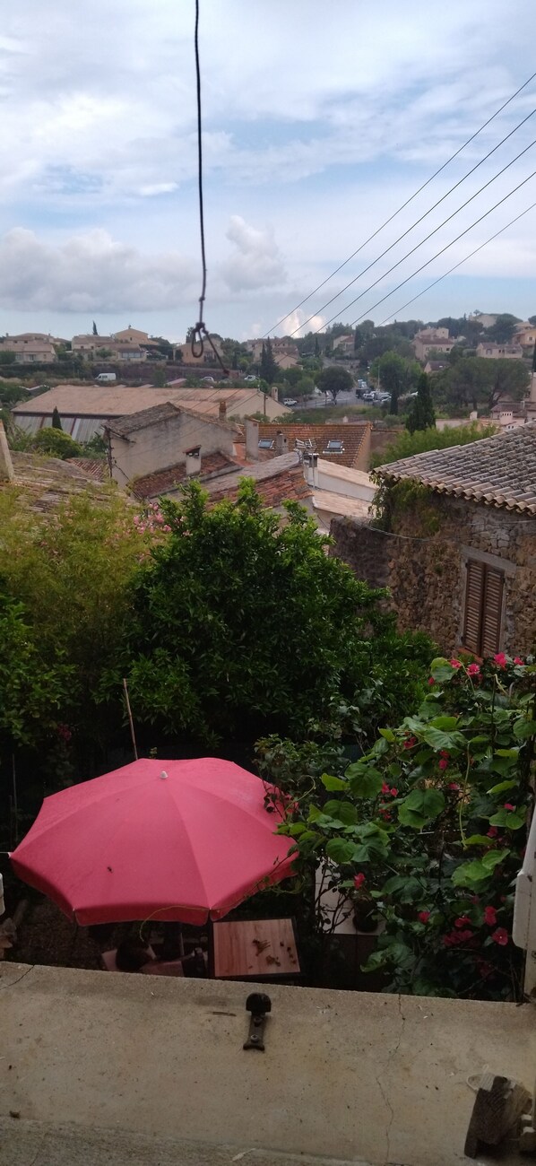 A red umbrella, a stone wall, and a view of houses and greenery.