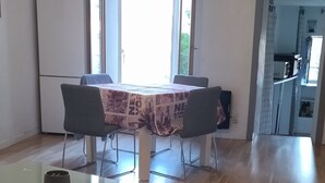 A spacious living area with a dining table, a sofa, and a kitchen in the background. - Charmant Appartement de Village (Roquebrune-sur-Argens)