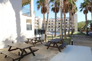 Outdoor picnic tables, a pool, and a building with balconies. - Apartamento Paris (Miami Playa)