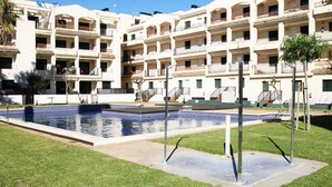 A multi-story hotel with a central swimming pool, outdoor seating, and a well-maintained lawn. - Apartamento Paris (Miami Playa)