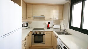 A compact kitchen with a built-in oven, microwave, and a washing machine. - Apartamento Paris (Miami Playa)