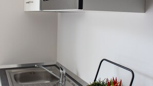Une cuisine équipée d’un évier en acier inoxydable, d’un four à micro-ondes et d’une jardinière en bois contenant des plantes.