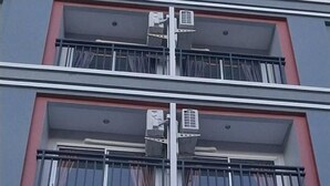 Un immeuble à plusieurs étages doté de balcons, de climatiseurs et de grandes fenêtres.