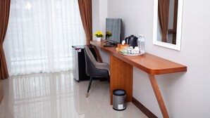 Une chambre d’hôtel équipée d’un bureau, d’une chaise, d’une télévision, d’une machine à café et d’une poubelle.