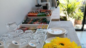 Une table avec des tasses et des assiettes blanches, ainsi qu’un vase rempli de fleurs jaunes.