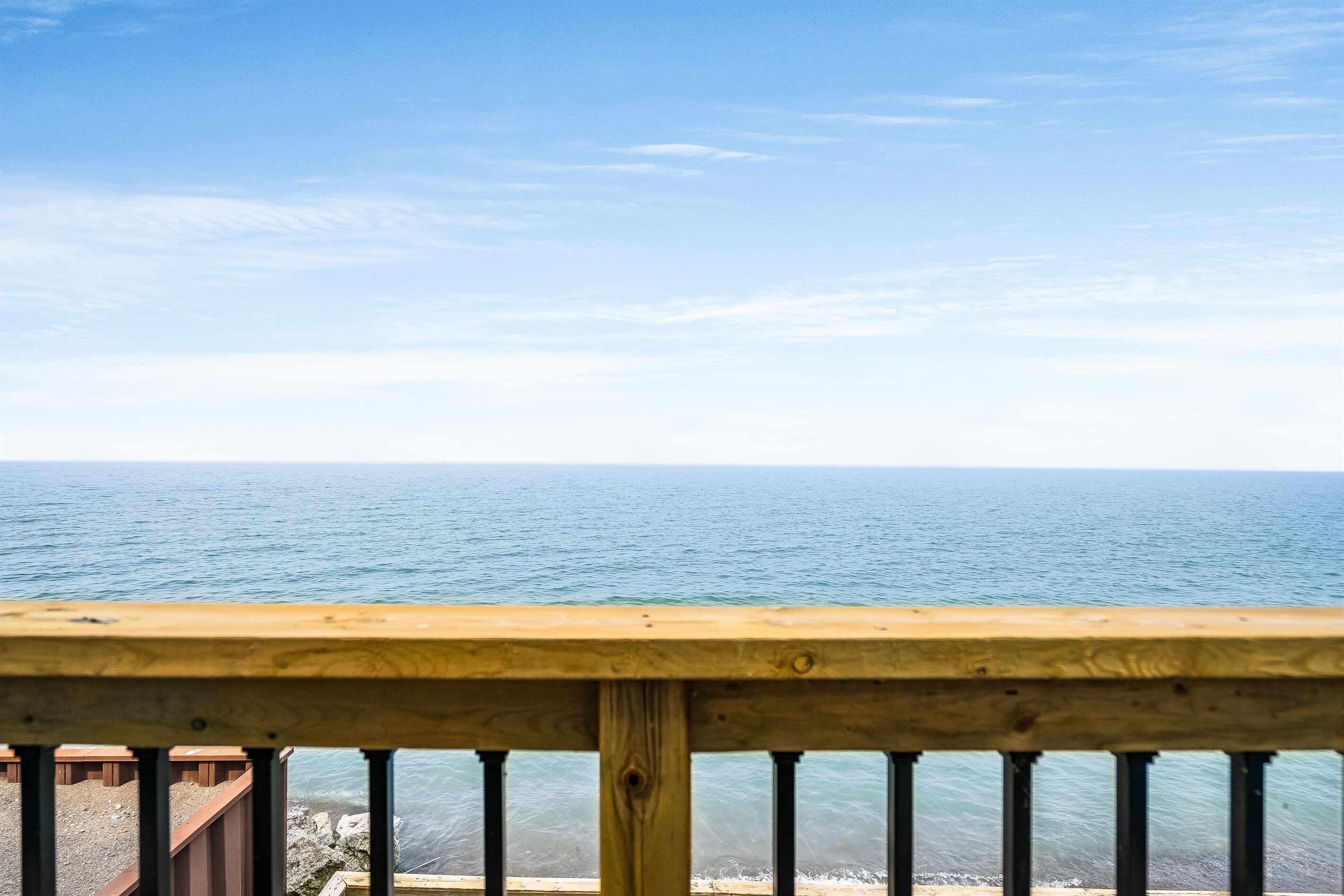 Barandilla de madera con vistas al mar tranquilo.