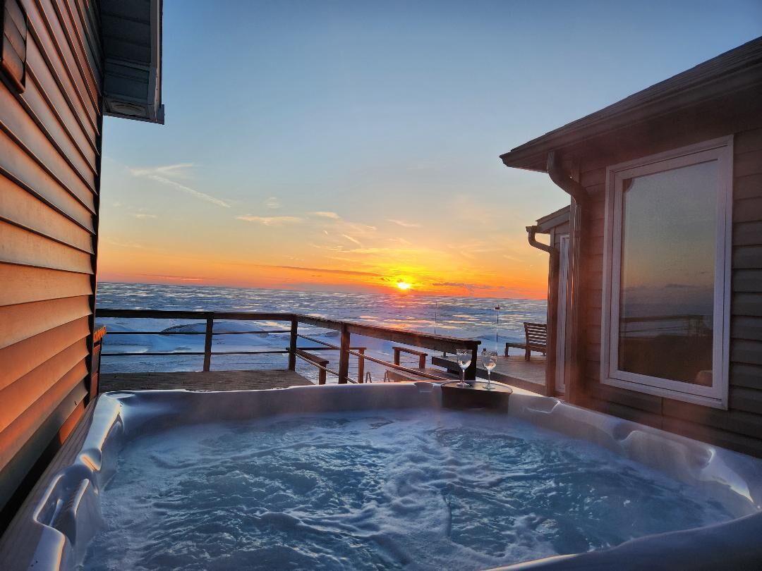 A hot tub on a deck with a sunset view.