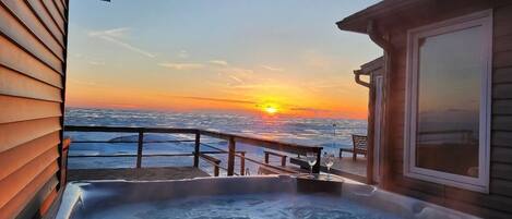 A hot tub on a deck with a sunset view.