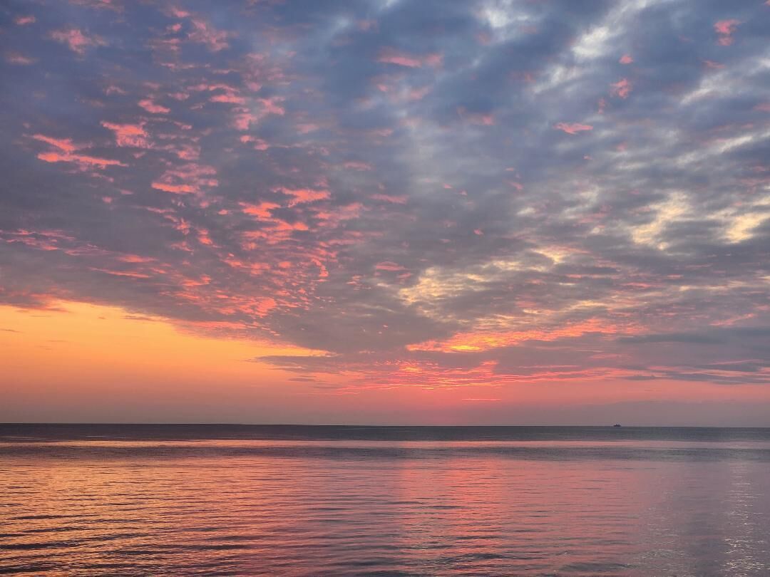 A sunset over a calm sea with a clear horizon.