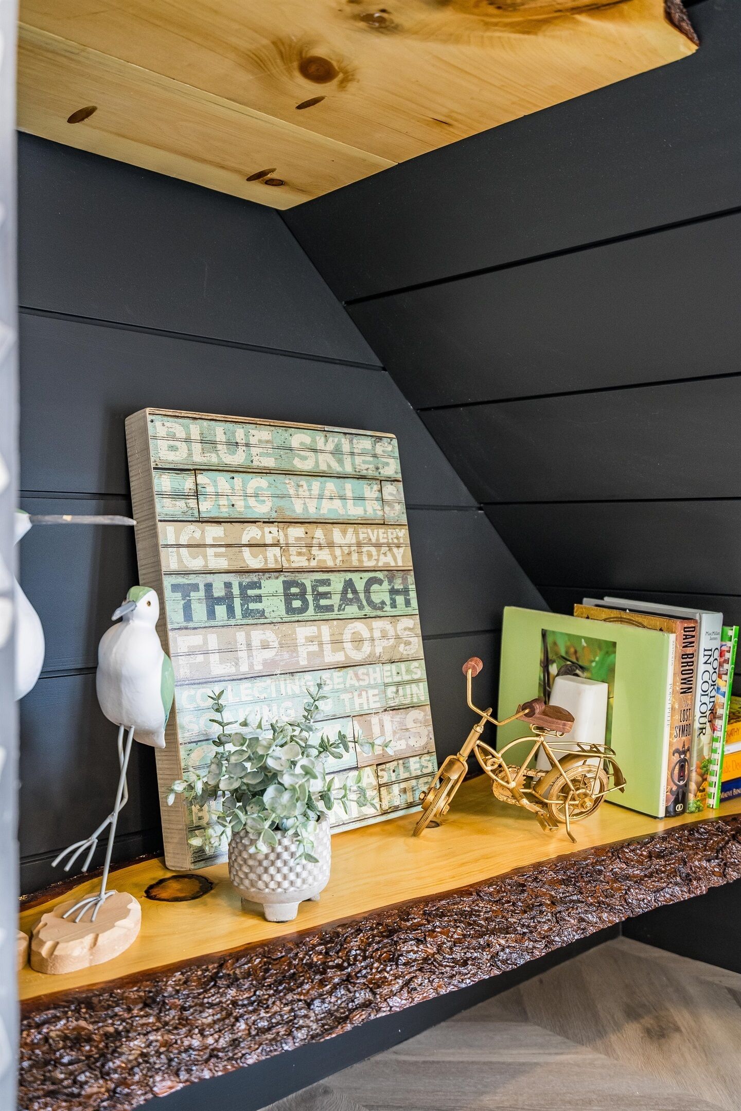 A wooden shelf with a sign reading "Blue Sky Long Walk Ice Creamery," a white bird figurine, a potted plant, and a bicycle.