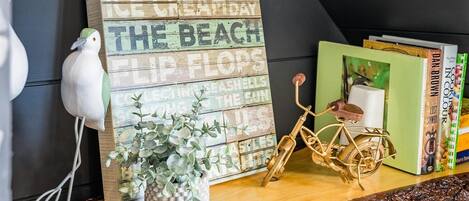 A wooden shelf with a sign reading "Blue Sky Long Walk Ice Creamery," a white bird figurine, a potted plant, and a bicycle.