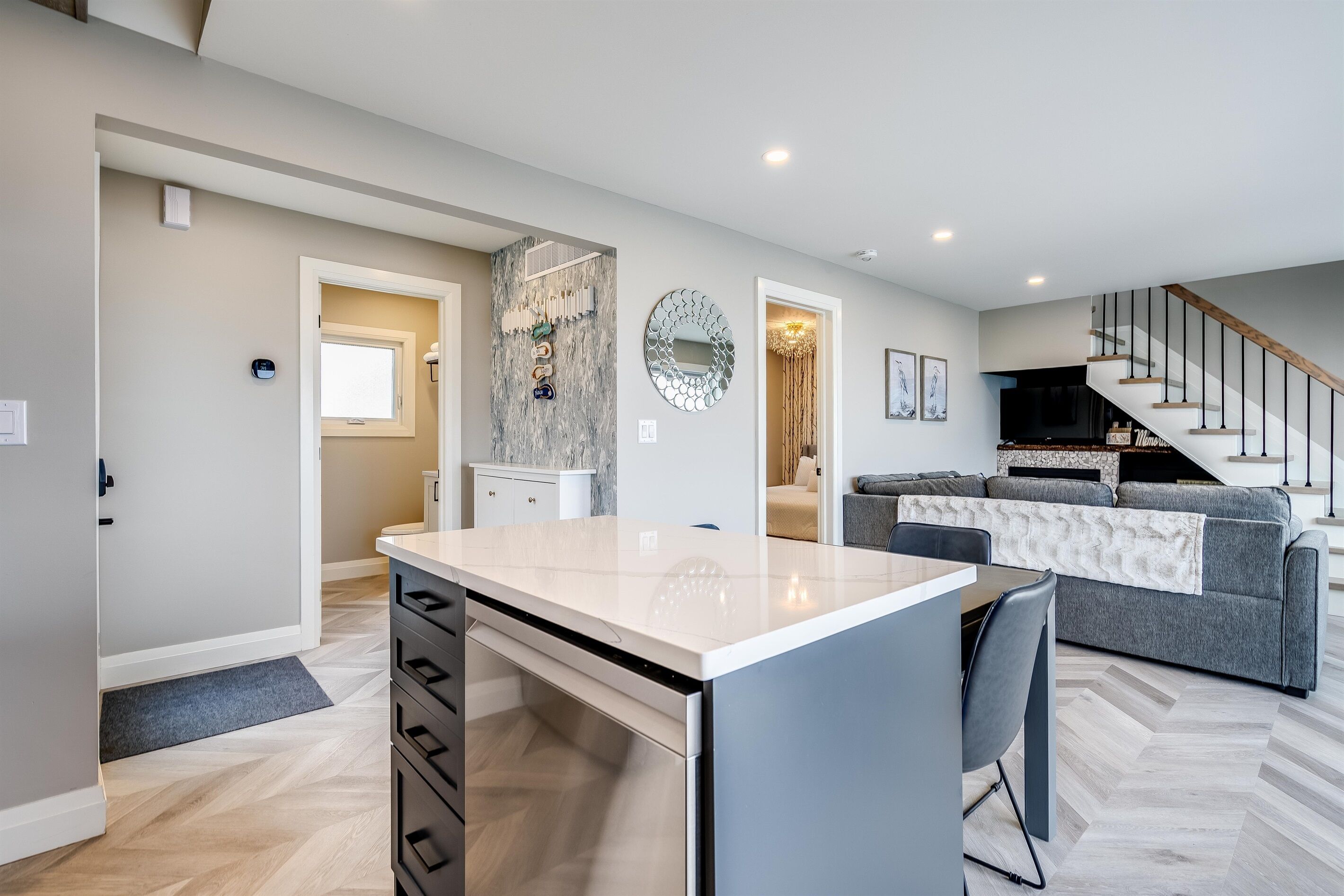 A modern kitchen with a marble countertop, a built-in dishwasher, and a gray dining area.