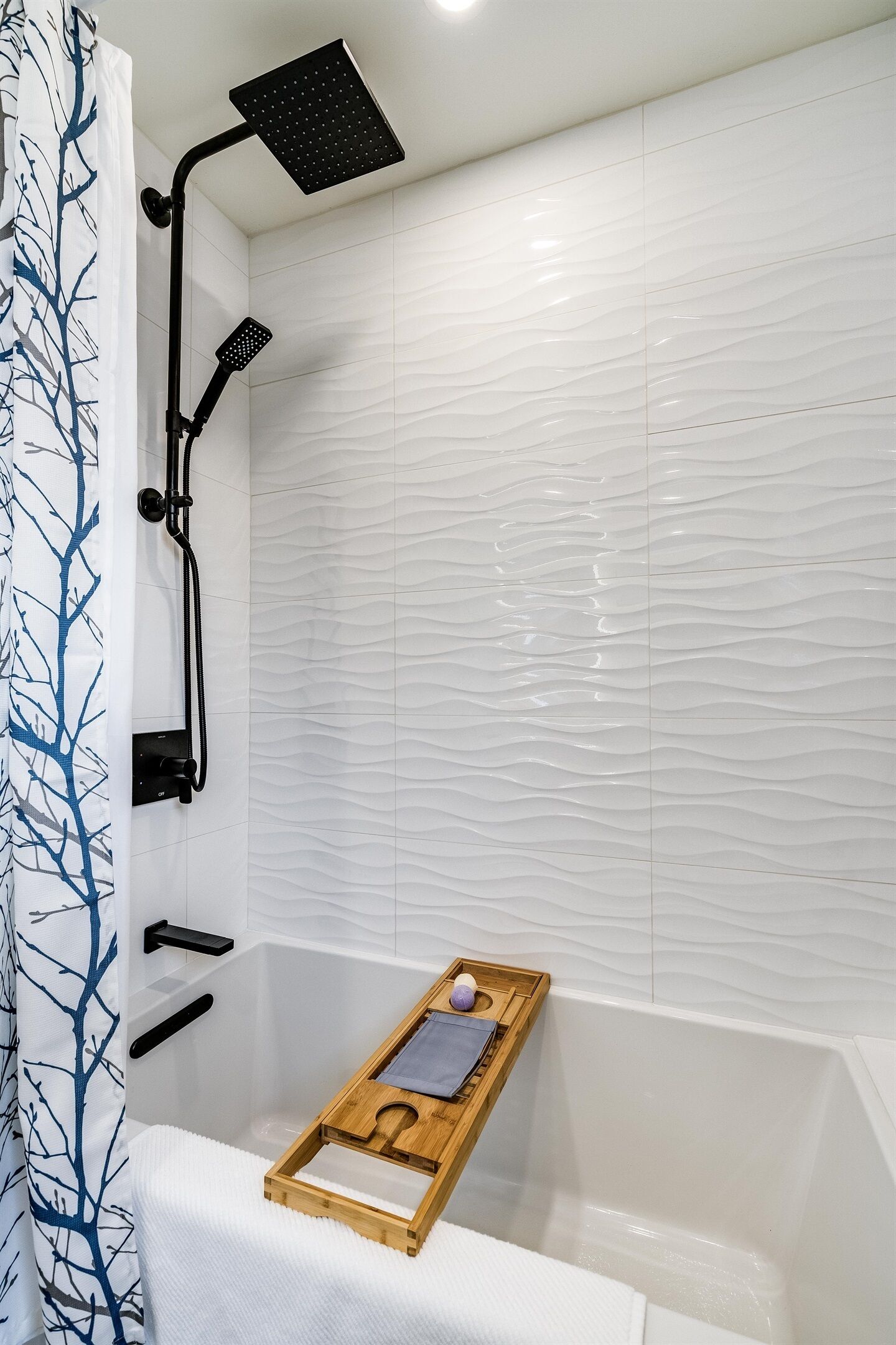 Ein modernes Badezimmer mit Dusche, einem Holftablett mit Pflegeprodukten und einer weißen Fliesenwand.