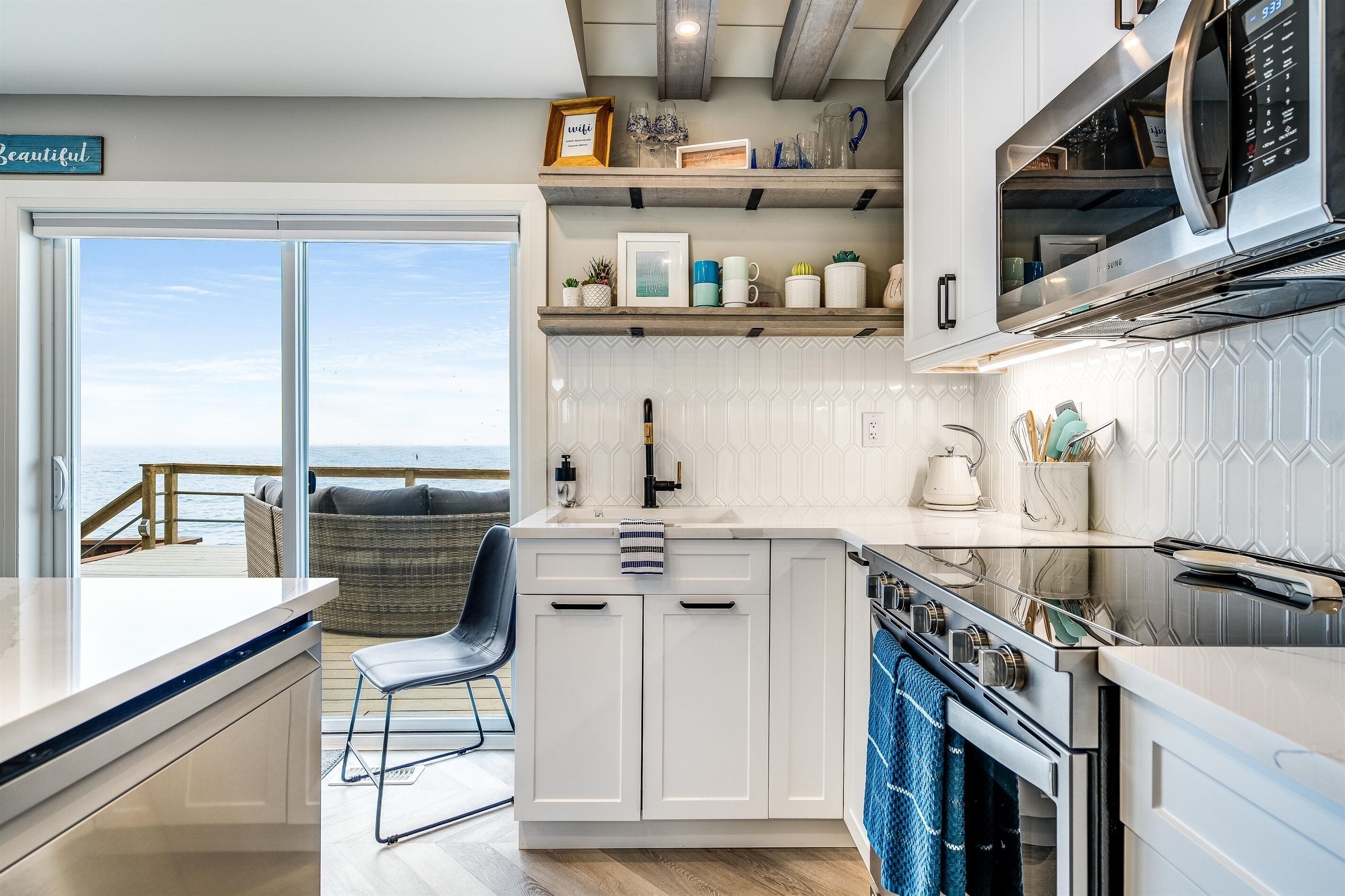 A modern kitchen with white cabinetry, a built-in microwave, and a view to the outside.
