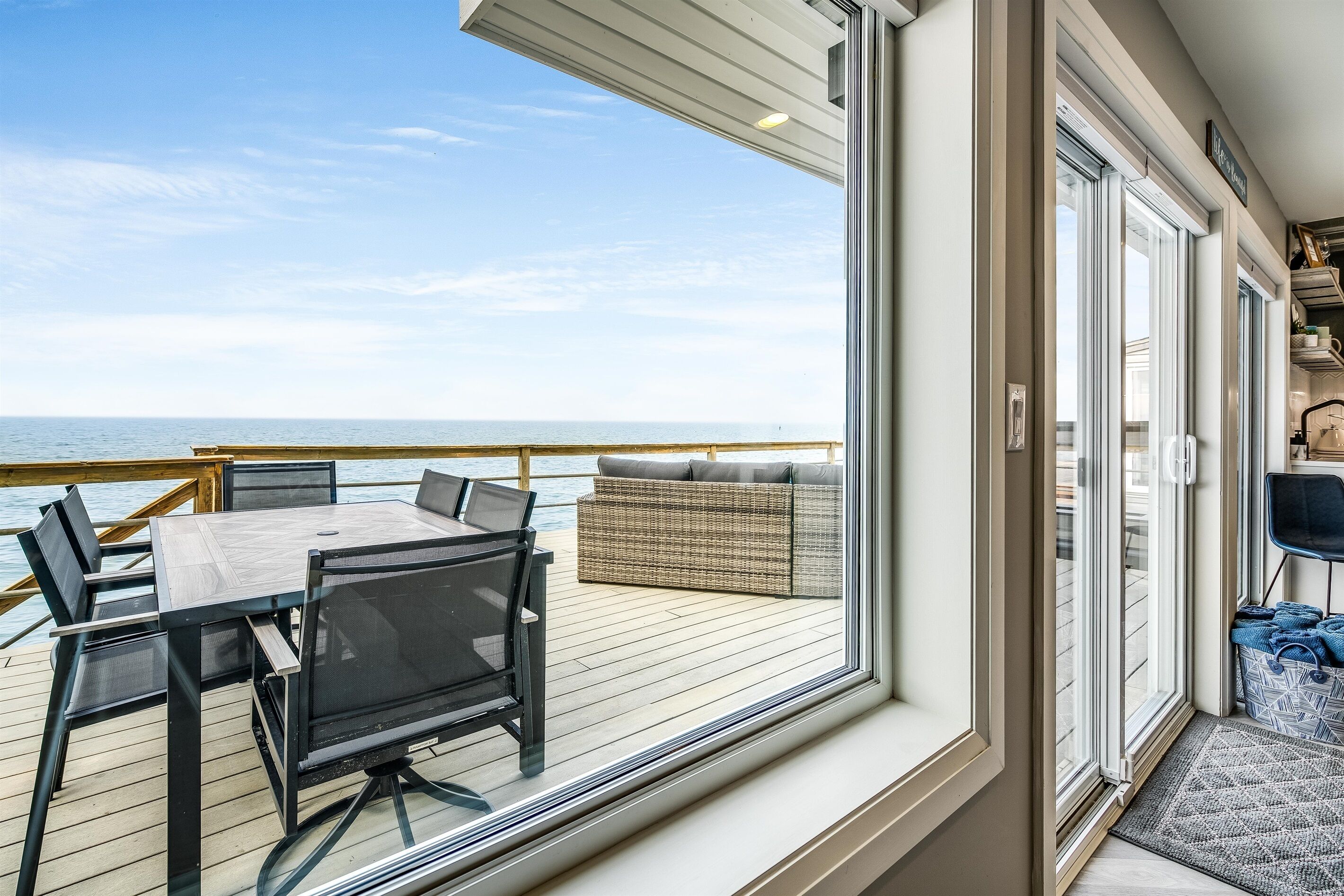 A deck with a table and chairs, a wicker sofa, and a view of the ocean.