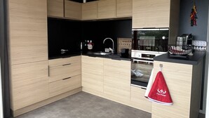 A modern kitchen with light wood cabinets, a black countertop, a Bosch oven, and a sink. - Chalet Eguskitsua avec piscine (Hasparren)