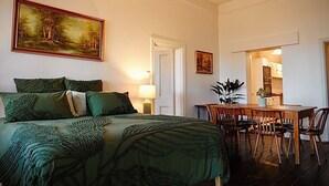 Une chambre à coucher avec un lit, une literie verte, un tableau, un bureau et une chaise.