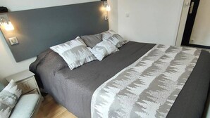 A modern bedroom with a large bed, a nightstand, and a chair. - Lovely T2 apartment in Cauterets for 2 people (Cauterets)