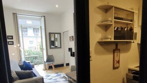 A living room with a sofa, a chair, a small table, and a kitchen area with shelves. - Lovely T2 apartment in Cauterets for 2 people (Cauterets)