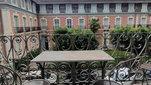 A courtyard with a table and chairs, surrounded by ornate metal railings, and a building with multiple windows in the background. - Lovely T2 apartment in Cauterets for 2 people (Cauterets)