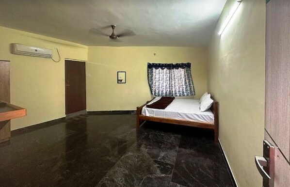 Ein Zimmer mit einem Bett, einem Deckenventilator, einer Klimaanlage und einer Tür.