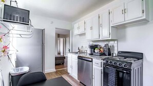 Una cucina moderna con mobili bianchi, un piano cottura nero ed elettrodomestici in acciaio inossidabile.