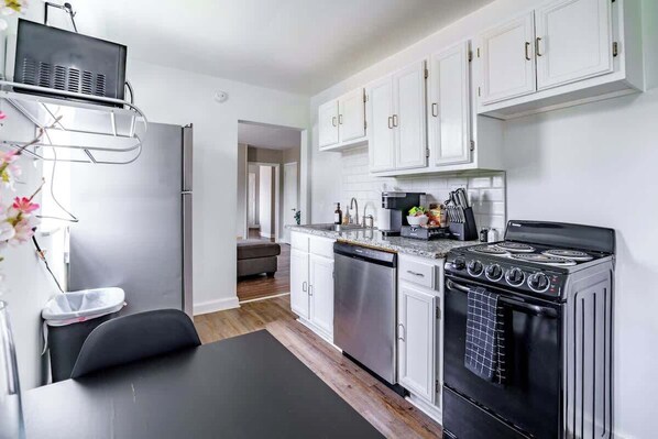 Una cocina moderna con armarios blancos, una estufa negra y electrodomésticos de acero inoxidable.