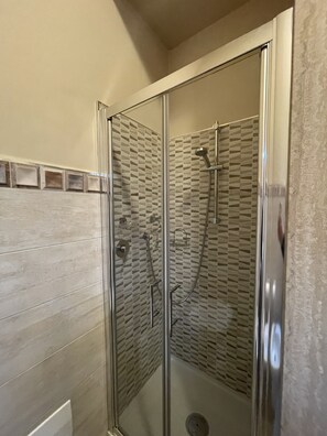 A glass-enclosed shower with a geometric tile backsplash and a wooden panel wall. - 10 minutes from the historic center Modern apartment with with private parking space (Spoleto)