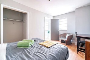 Um quarto com cama, cadeira, mesa e guarda-roupa.