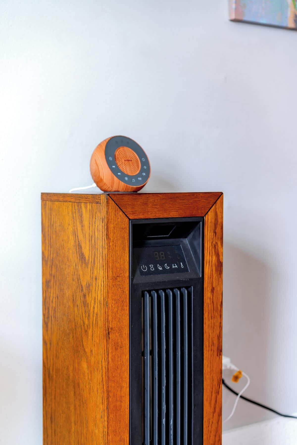 A wooden speaker with a digital display and a circular knob on top.
