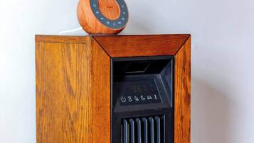 A wooden speaker with a digital display and a circular knob on top.