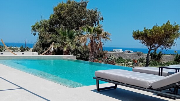 A pool with lounge chairs and a view of the sea. - Echo Villa (Santorini)