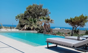 A pool with lounge chairs and a view of the sea. - Echo Villa (Santorini)
