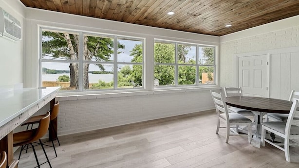 A room with a large window, a dining table, chairs, and a wooden ceiling. - Sunset Cove- Lake Home, Dock, Fire Pit, Hot Tub, Game Room, Etc (Winchester)