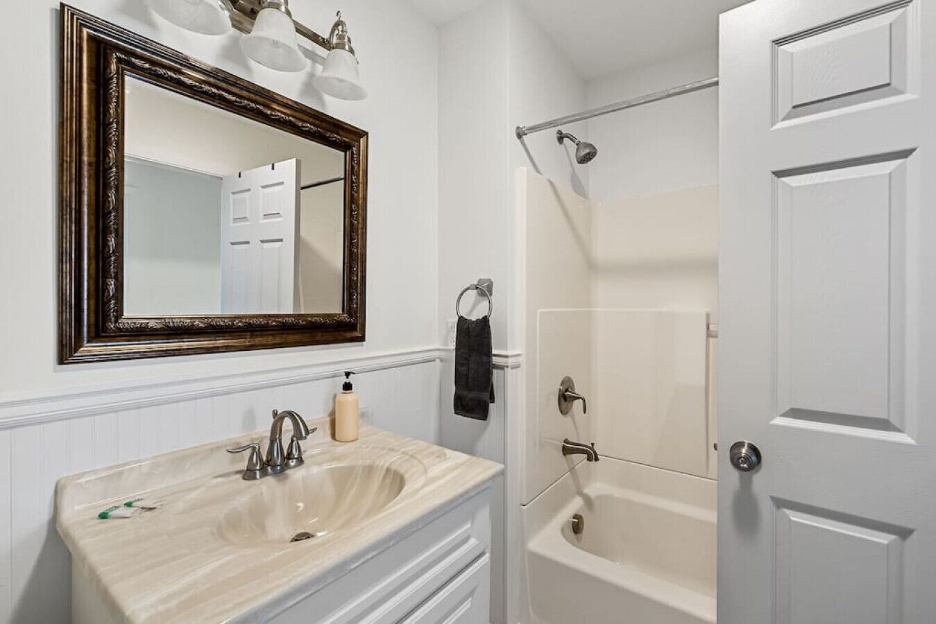 A bathroom with a large mirror, a sink, a bathtub, and a shower.