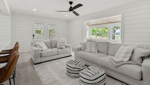 A modern living room with two sofas, a dining table, and a ceiling fan. - Sunset Cove- Lake Home, Dock, Fire Pit, Hot Tub, Game Room, Etc (Winchester)