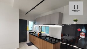 Een moderne keuken met een centraal eiland, een eethoek met een zwarte koelkast, en een bordje dat een vakantie appartement aangeeft.