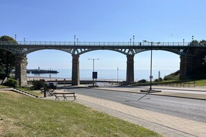 Walk across the bridge and take in the serene views of the water below, surrounded by lush greenery and street lamps.