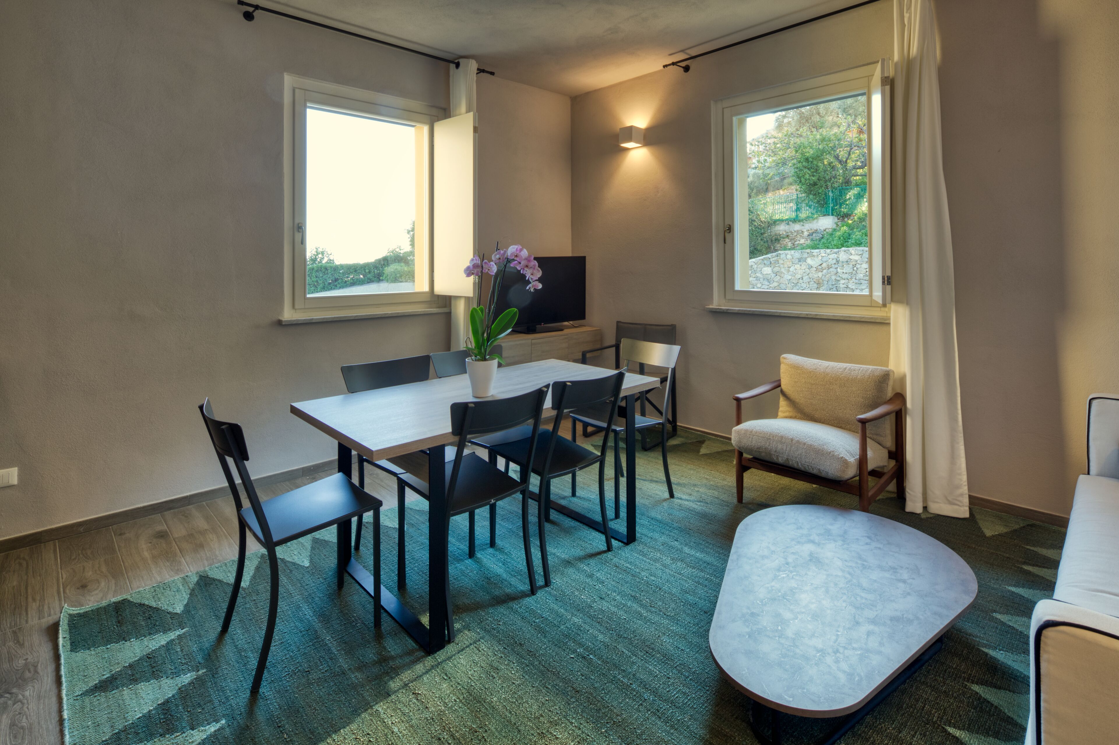 A modern room with a dining table, chairs, a sofa, and a TV.