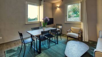 A modern room with a dining table, chairs, a sofa, and a TV.